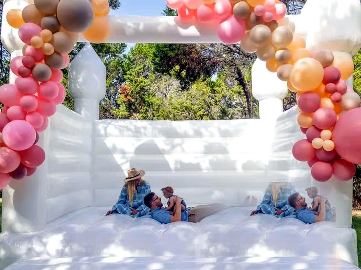 A styled all-white bounce house set against soft blush and floral décor at a Columbia celebration