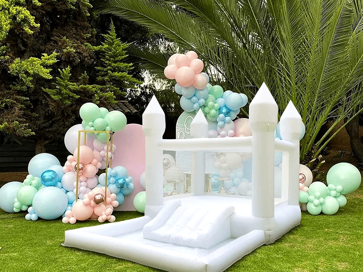 The Hartwell Petite, a small all-white castle bounce house with a bishop-top peak, built-in slide, and ball pit for toddlers
